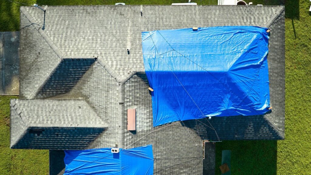 roof needing emergency commercial roofing, with a tarp over the damage